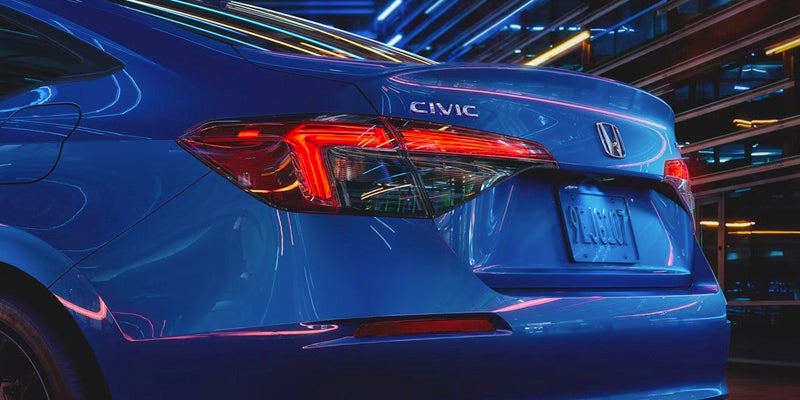 the trunk of a blue 2024 Civic Sedan surrounded by neon lights with CIVIC visible on the car's trunk